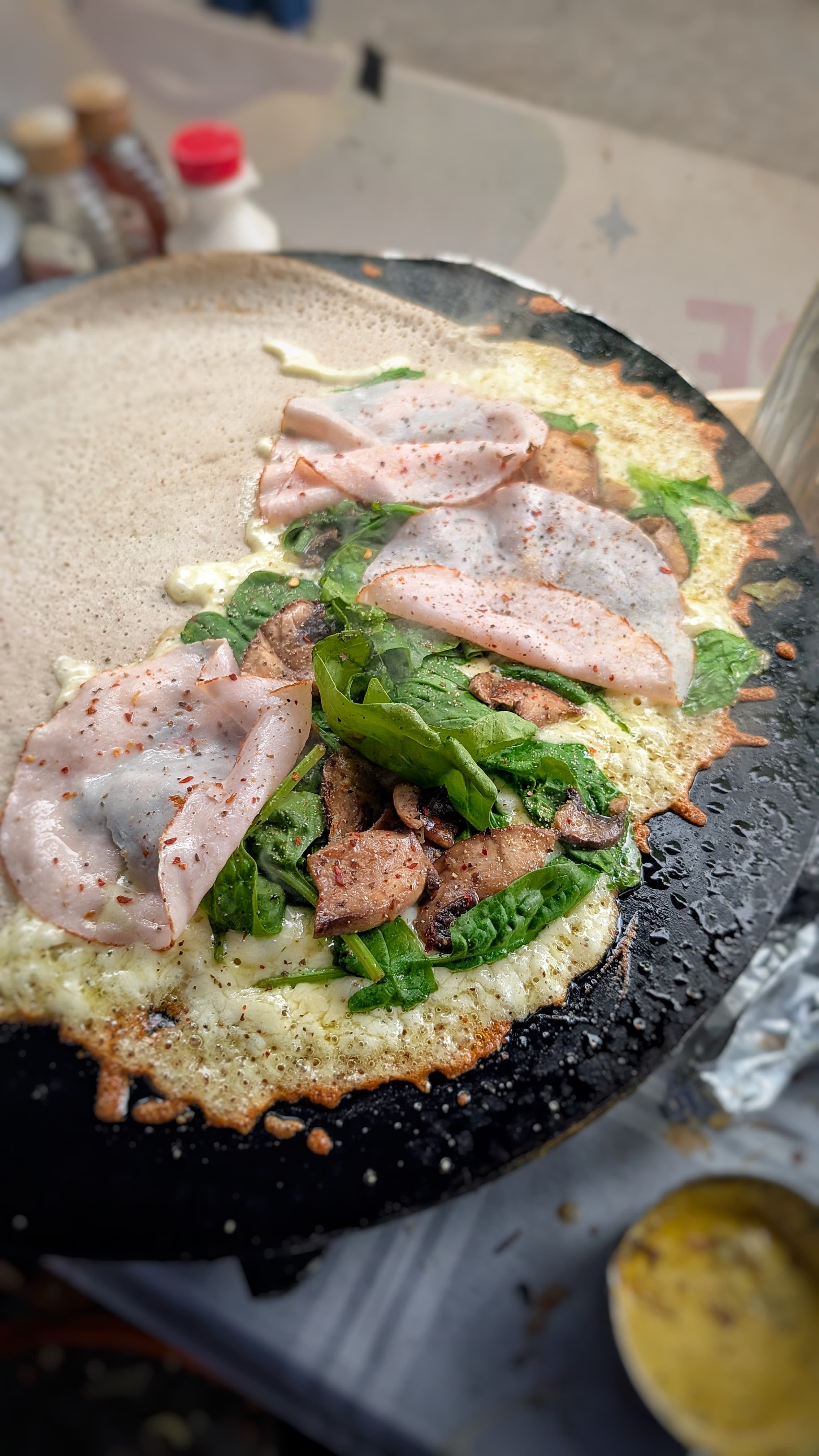 Open crêpe with smoked ham, fresh spinach and wild mushrooms, moments before the fold